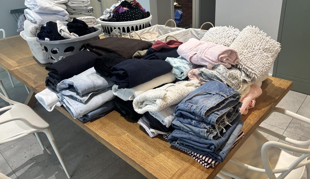 Neatly folded clothes sorted by type on a dining table
