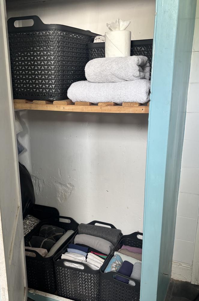 A cupboard with towels and clothes folded neatly into baskets