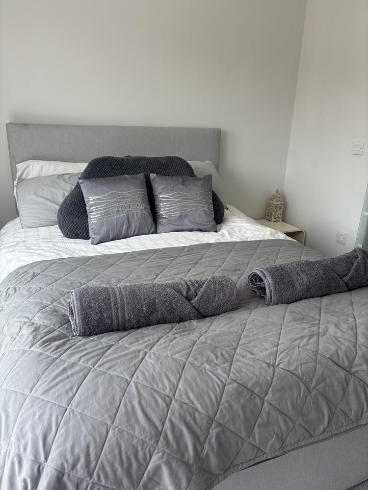 A freshly made bed with rolled towels laid out for guests