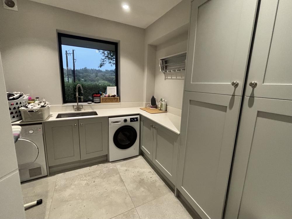 A tidy utility room with grey cabinets and a clear worktop